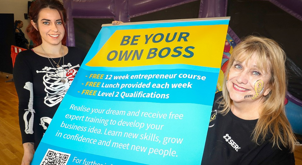 two people holding a sign displaying the text be your own boss